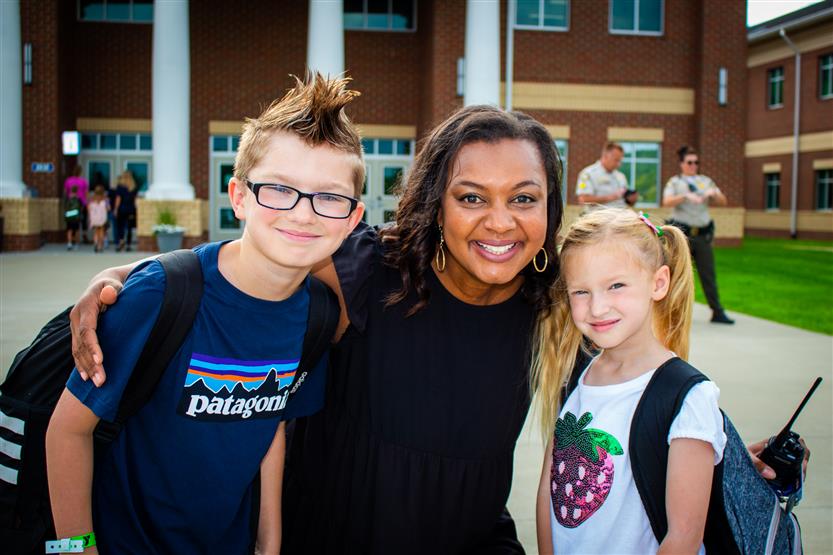 Two students smile with the principal
